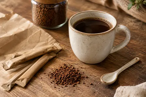 Tasse de café soluble accompagnée de sticks individuels sur un comptoir en bois