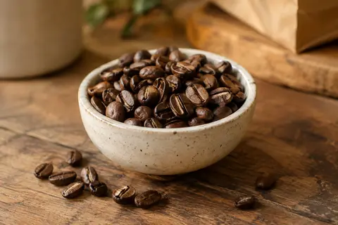 Grains de café Arabica entiers dans une coupelle en céramique sur un comptoir en bois