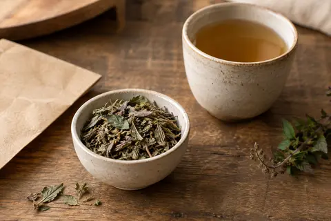 Feuilles séchées de tulsi en vrac dans un bol de céramique posé sur un comptoir en bois